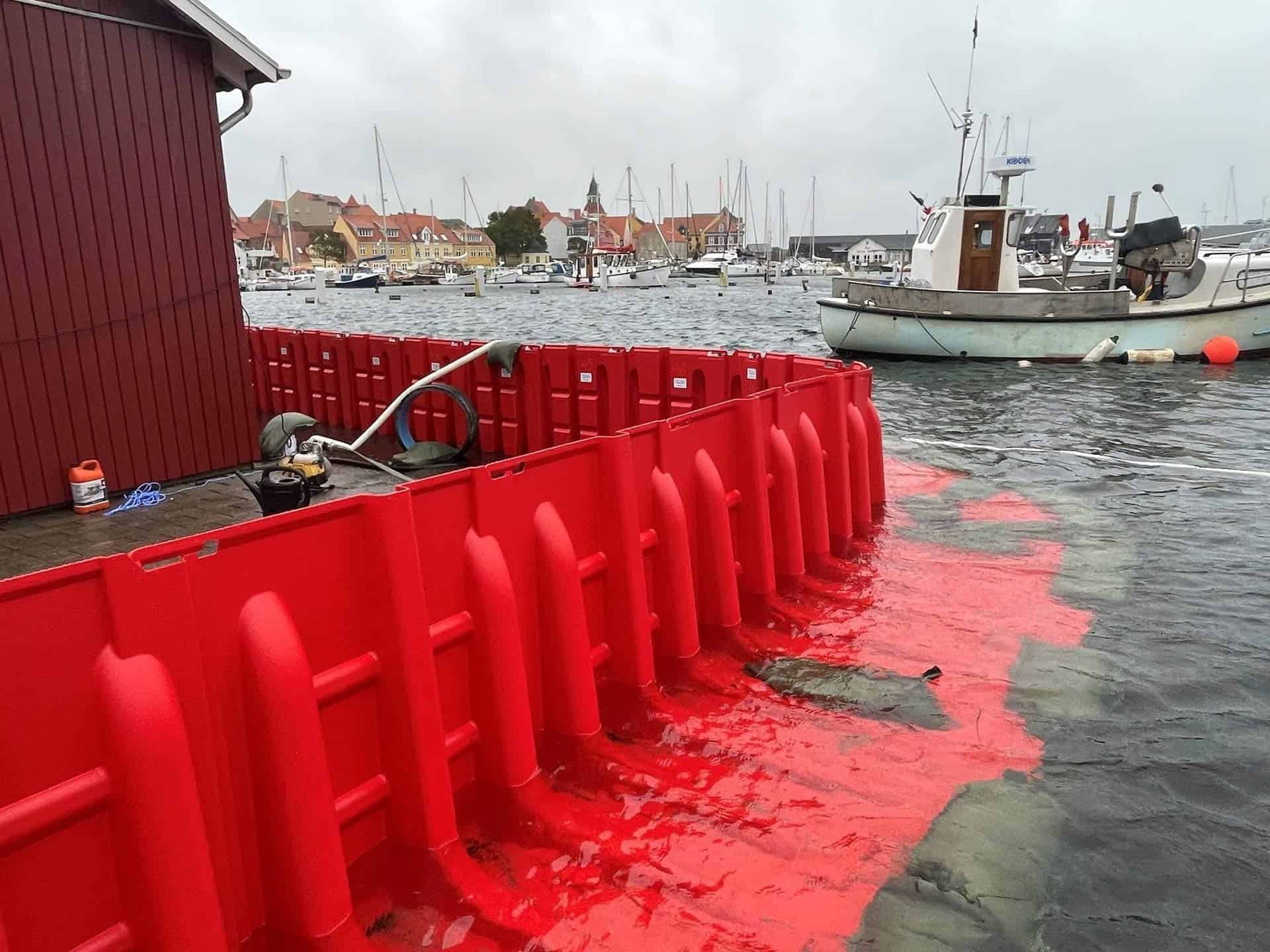 Mobil skybrudssikring beskytter rødt træhus langs havnekaj
