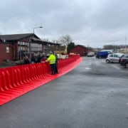 Lang række af Boxwall vandbarriere til bygning opstillet på våd asfalt